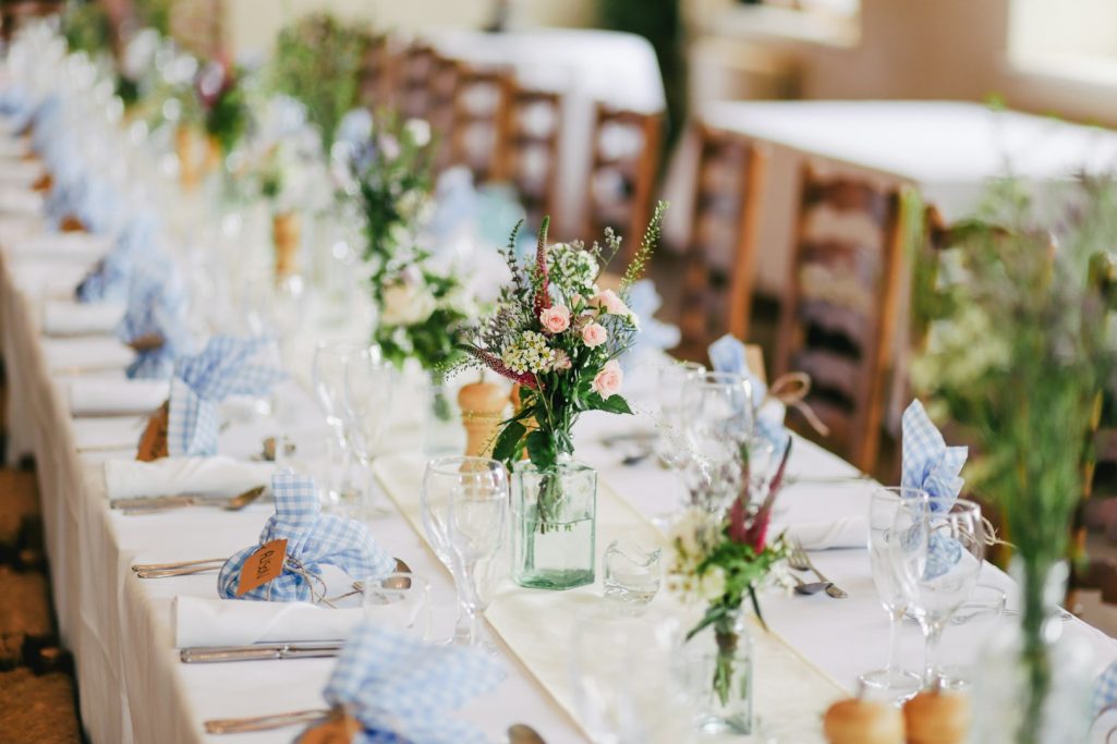 Elegant dining setup with flowers, neatly arranged tables, and blue napkins.