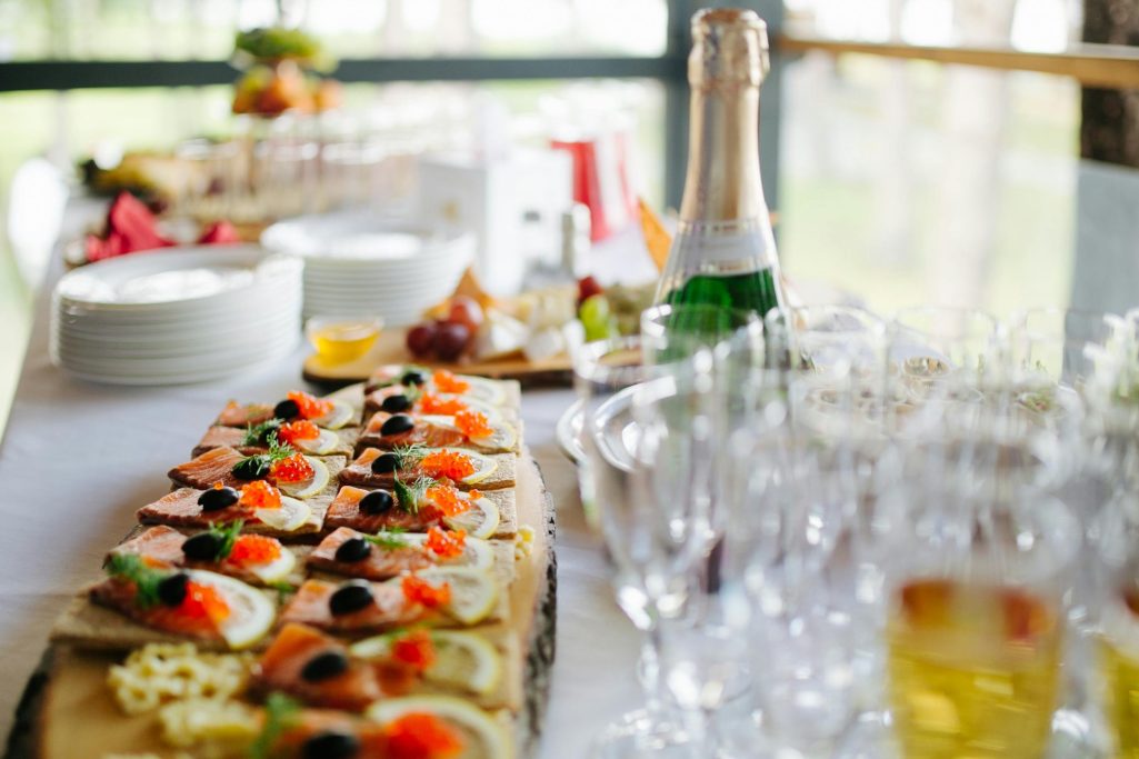 A buffet table with assorted appetizers, drinks, and glasses.